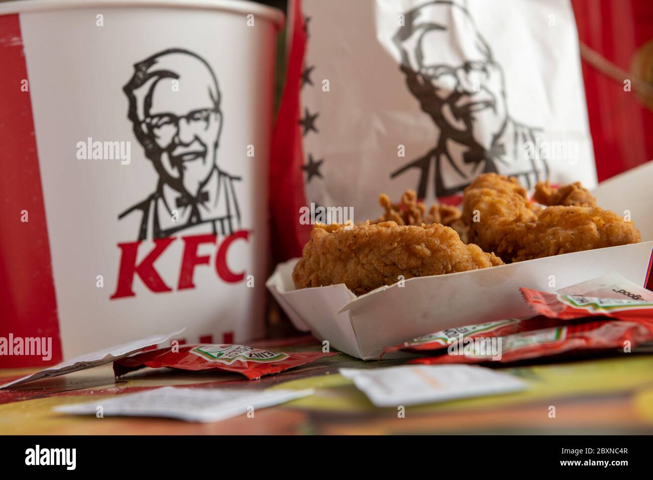Kentucky Fried Chicken, KFC, Filets mit Päckchen Tomatenketchup auf einer Tischplatte und Eimer und Tasche mit dem Firmenlogo und Marke. Stockfoto