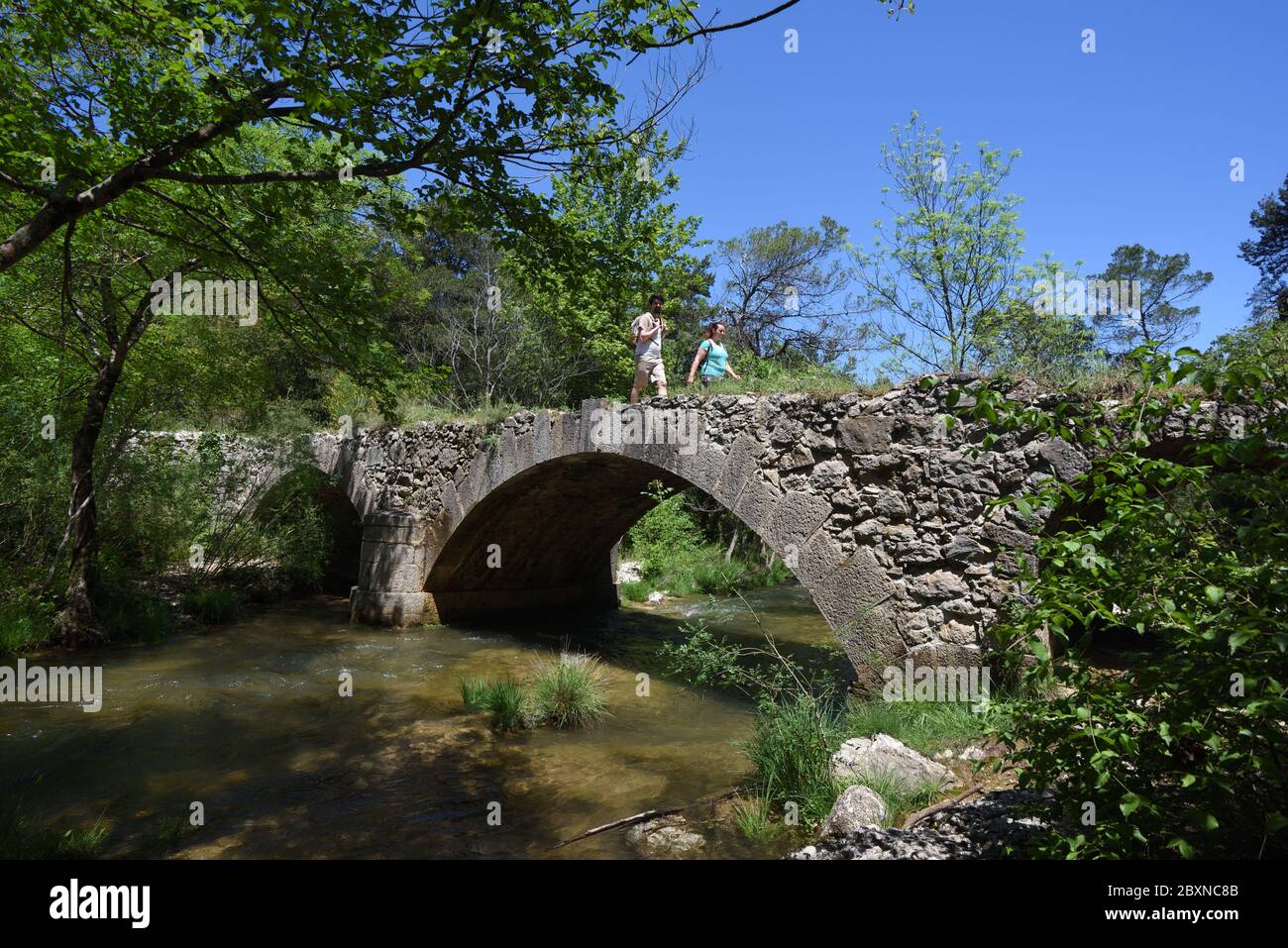 Ein paar Wanderer oder Touristen überqueren die römische Steinbrücke über den Fluss Caramy in Caramy Gorge Tourves Var Provence Frankreich Stockfoto