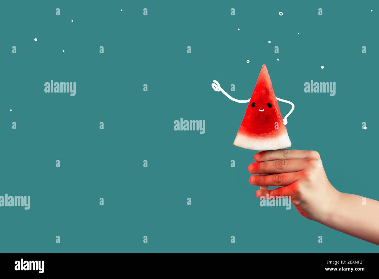 Hand hält ein Stück Wassermelone auf einem Stock wie Eis auf einem grünen Hintergrund. Stockfoto