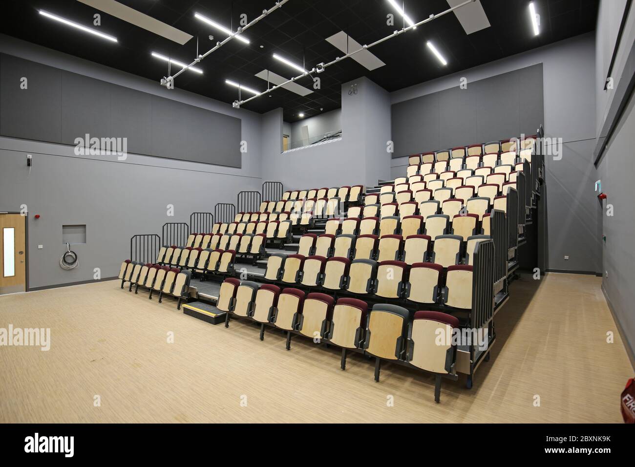 Ausziehbare Bleacher-Sitzmöbel in einer neu erbauten Schulhalle im Süden Londons, Großbritannien. Zeigt das System vollständig ausgefahren und bietet 9 Reihen gestufter Sitzplätze. Stockfoto