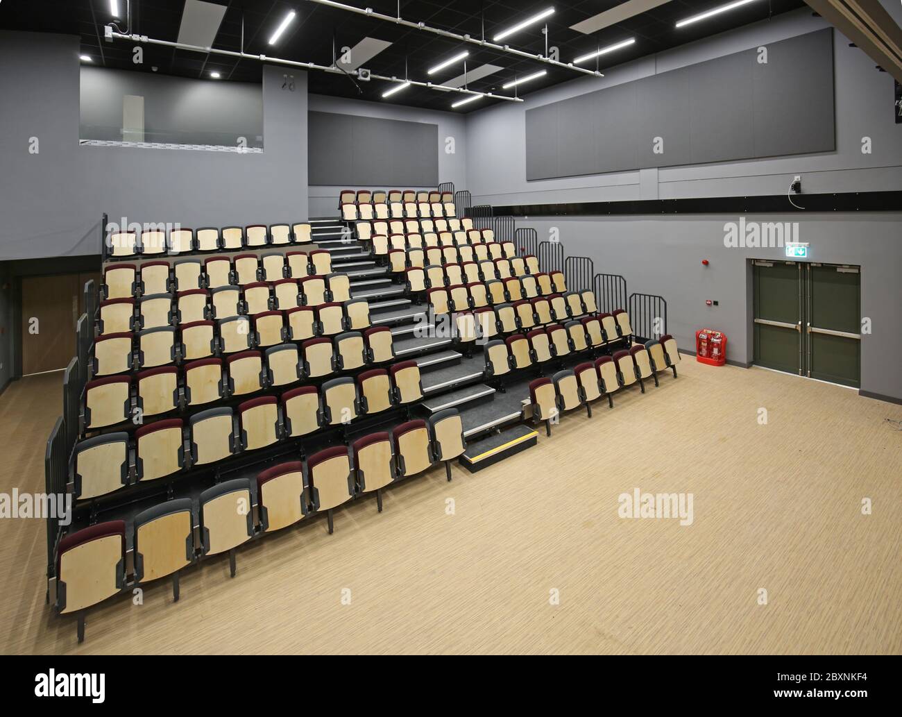 Ausziehbare Bleacher-Sitzmöbel in einer neu erbauten Schulhalle im Süden Londons, Großbritannien. Zeigt das System vollständig ausgefahren und bietet 9 Reihen gestufter Sitzplätze. Stockfoto