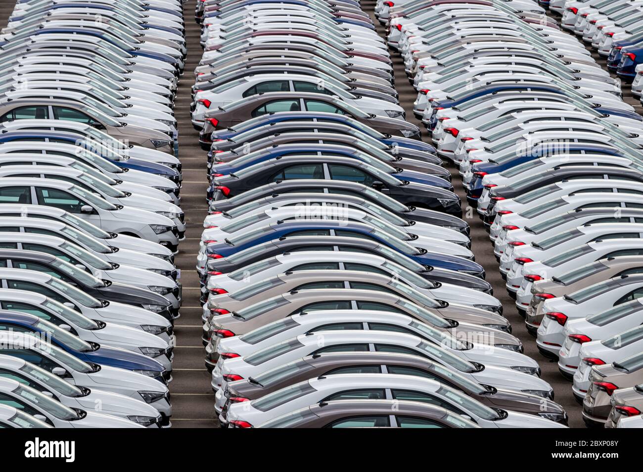 Reihen von Neuwagen, die an einem bewölkten Tag in einem Verteilzentrum