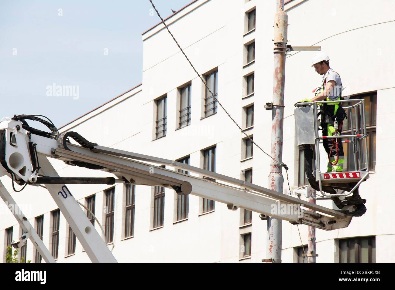 Belgrad, Serbien - 24. April 2020: Bauarbeiter im Krankorb, Kirschpflücker, Installation von Metallhalter auf Straßenlichtmast Stockfoto