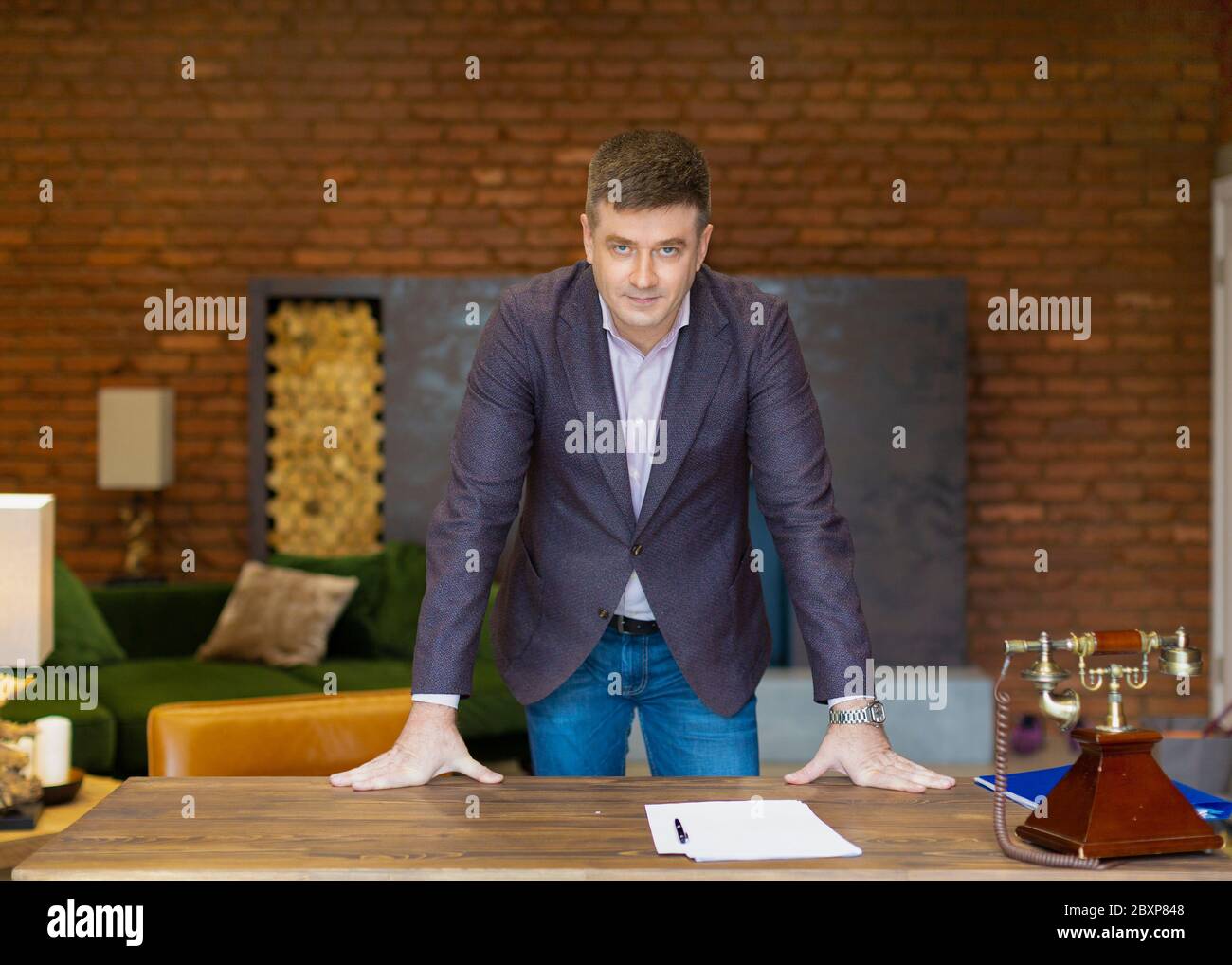 Porträt eines Geschäftsmannes mittleren Alters, der sich auf seinen Schreibtisch stützt. Geschäftskonzept. Stockfoto