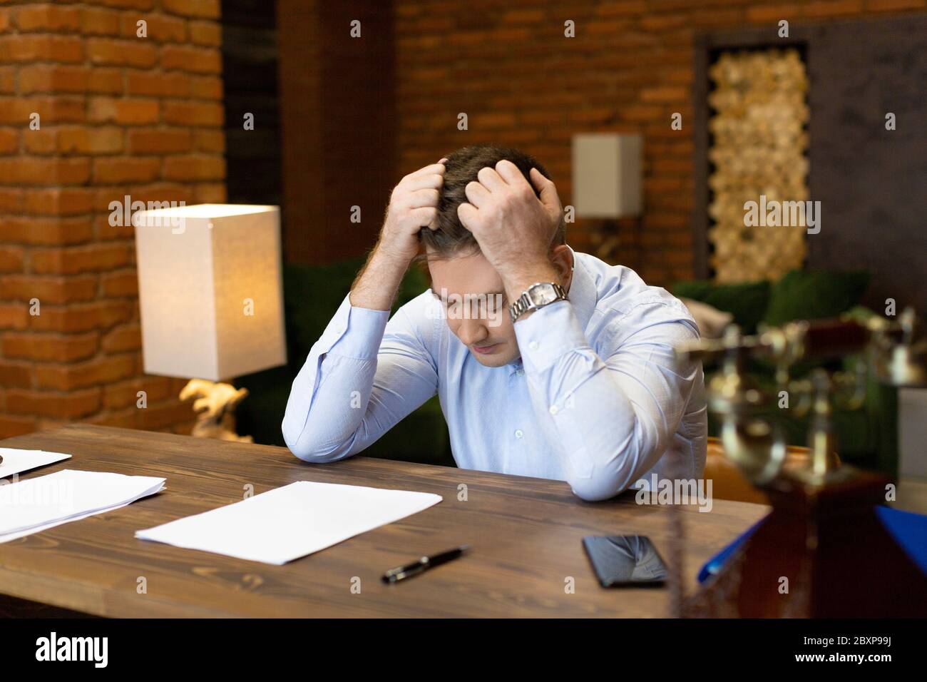 Kritischer Fehler in Dokumenten. Porträt eines Geschäftsmannes am Tisch, der seinen Kopf umklammert. Geschäftskonzept. Stockfoto
