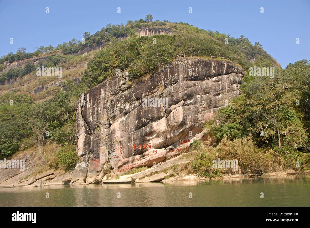 Wuyishan Gebirge in der Provinz Fujian, China. Felsen mit Inschriften und Dawang (Great King) Peak vom Nine Bends River oder dem Nine Twists Stream aus gesehen. Stockfoto