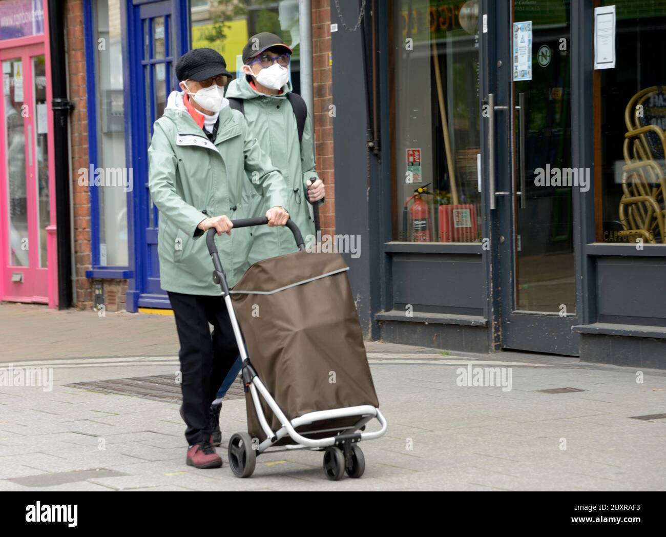 Zwei Frauen, in passenden Mänteln, mit Masken, einkaufen gehen. Stockfoto