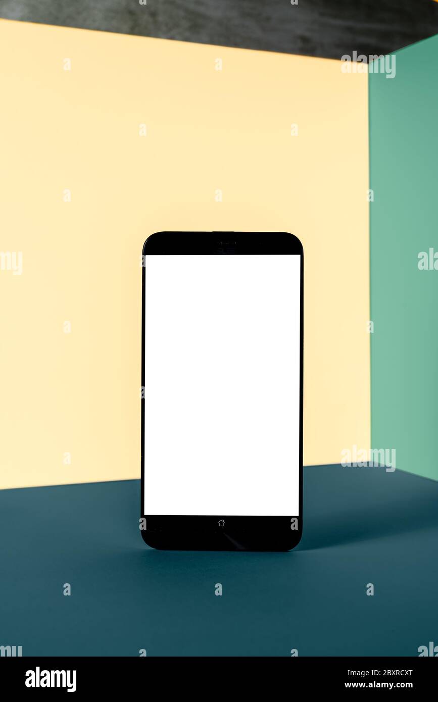 Minimalistisches modernes Smartphone-Modell für die Präsentation, in Perspektive vor dem Winkel der Ecke der bunten Wand, mit überlappenden Schatten. Applica Stockfoto