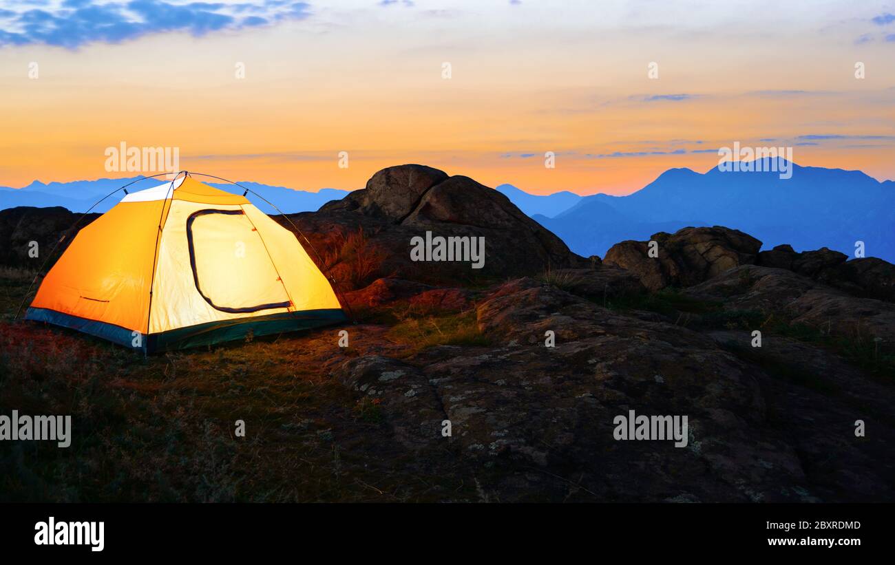 Gelb beleuchtet Zelt in der beautirul Abend Berge. Abenteuer und Reisen Konzept. Stockfoto