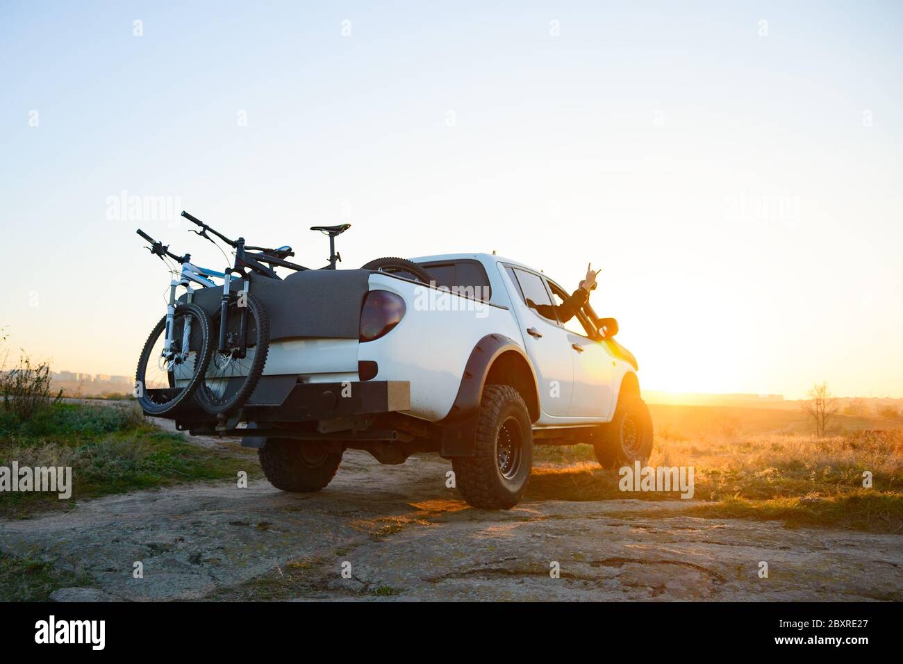 Freunde fahren den Pickup Offroad Truck in den Bergen mit Bikes im Körper bei warmem Herbstuntergang. MTB Abenteuer und Car Travel Konzept. Stockfoto