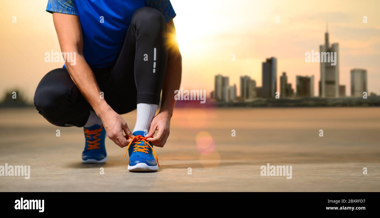 Junge männliche Sportler binden Laufschuhe und Vorbereitung für den Lauf bei Sonnenuntergang. Rest von Urban Lifestyle und Active Sport Konzept. Stockfoto