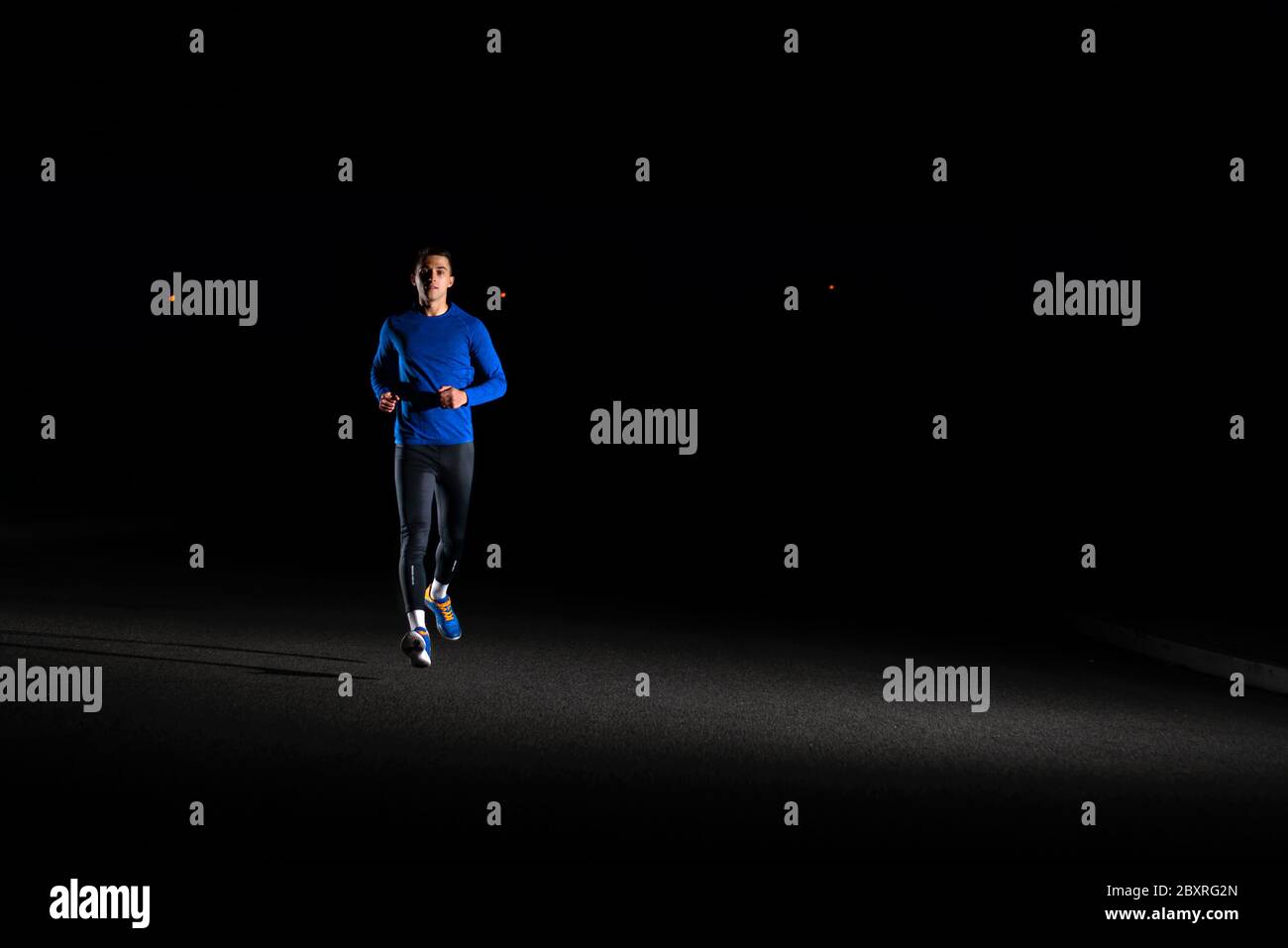 Junger Mann in Blau läuft nachts draußen. Urban Running. Gesundes Lifestyle- und Sportkonzept. Stockfoto