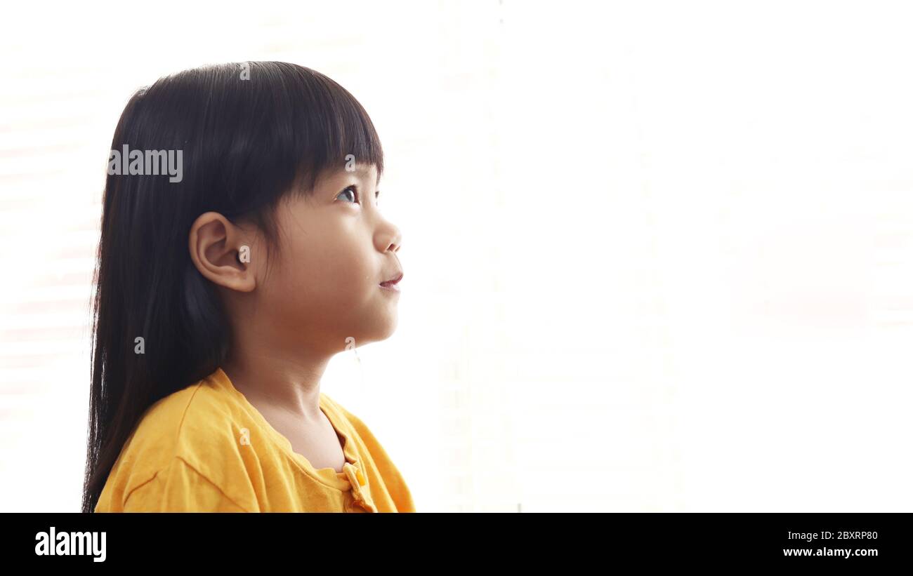 Nette kleine asiatische Baby Mädchen suchen nach oben Denken etwas isoliert auf weißem Hintergrund, Seitenprofil. Hope Konzept mit Kopierraum Stockfoto