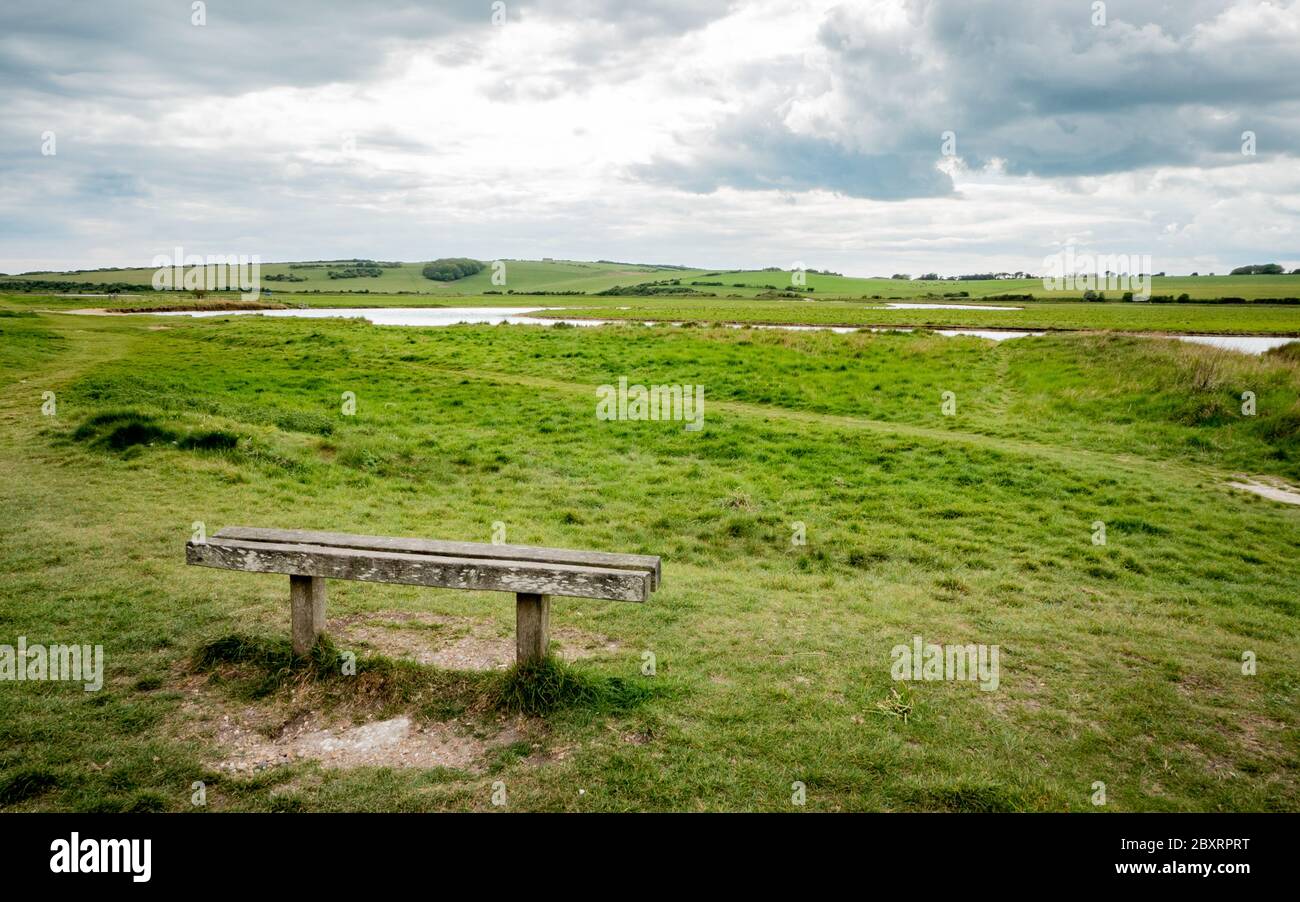 Bank mit Blick auf die South Downs, England. Die Hochwasserebenen von Cuckmere Haven im South Downs Nationalpark an der Südküste Englands. Stockfoto