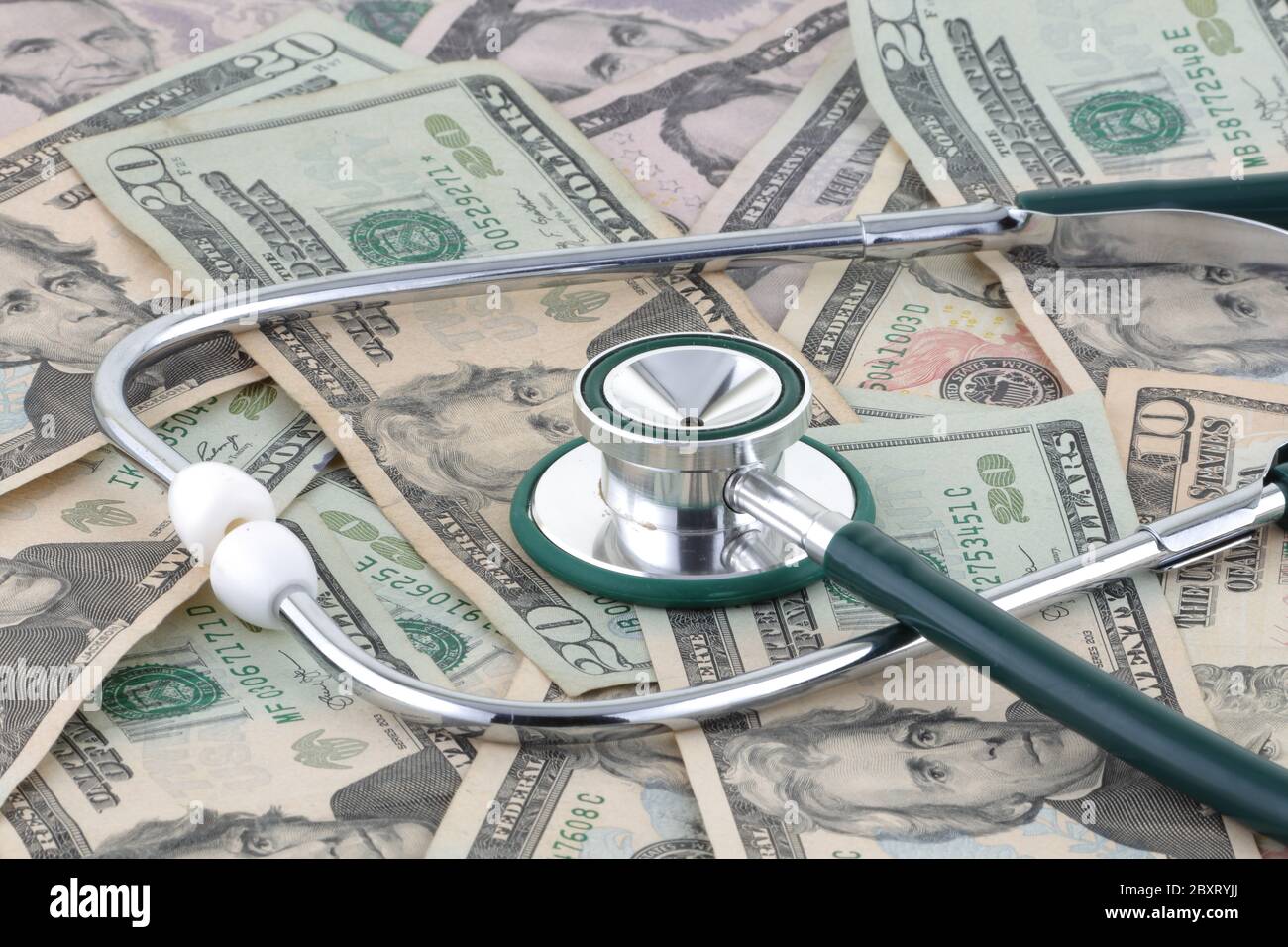 Medizinisches Stethoskop auf einem Geldhaufen, das das Verhältnis von Geld und Medizin anzeigt Stockfoto