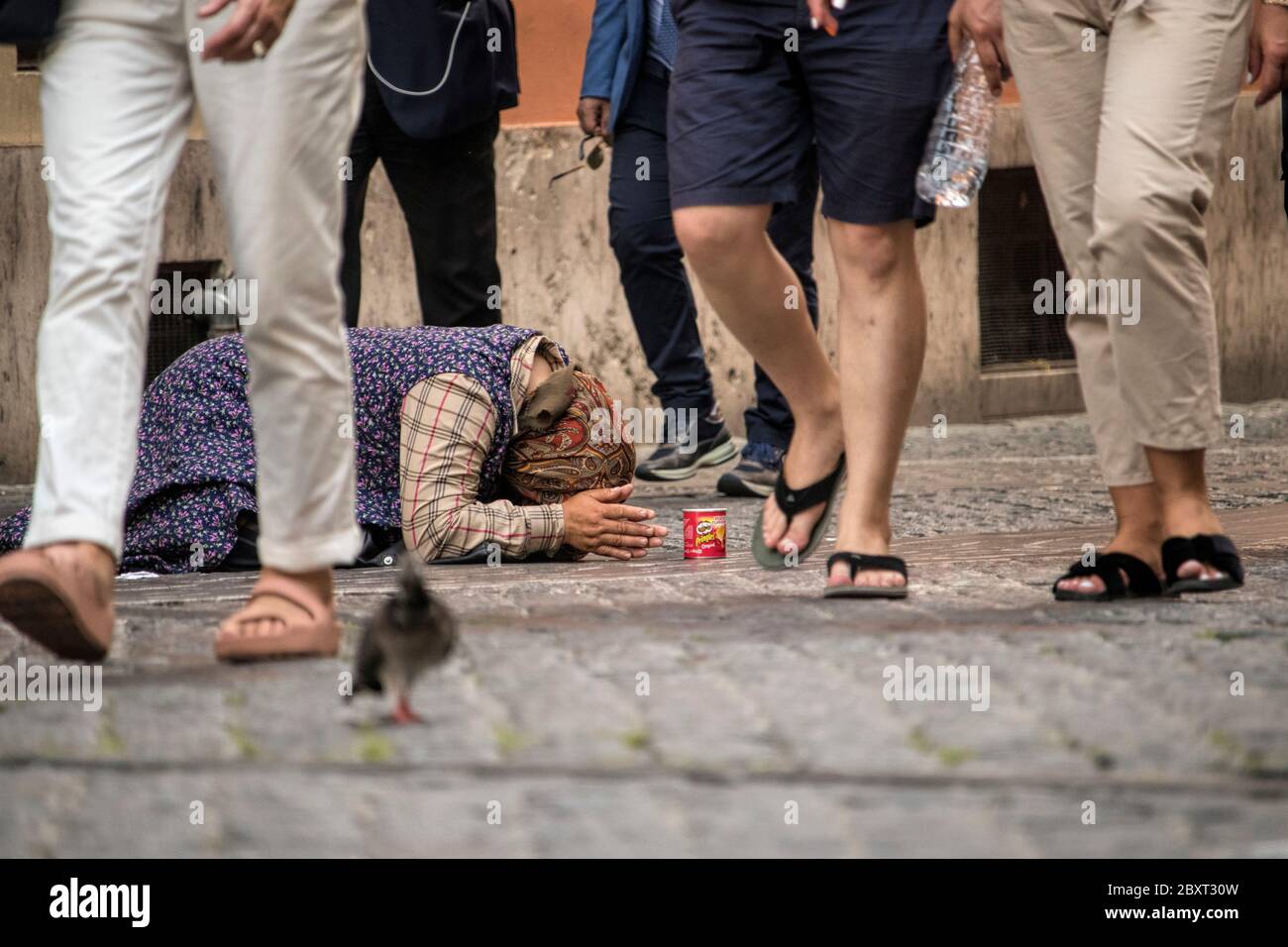 Ein Bettler, der auf dem Weg unter gleichgültigen Passanten in Rom, Italien, zu Boden geworfen wurde Stockfoto