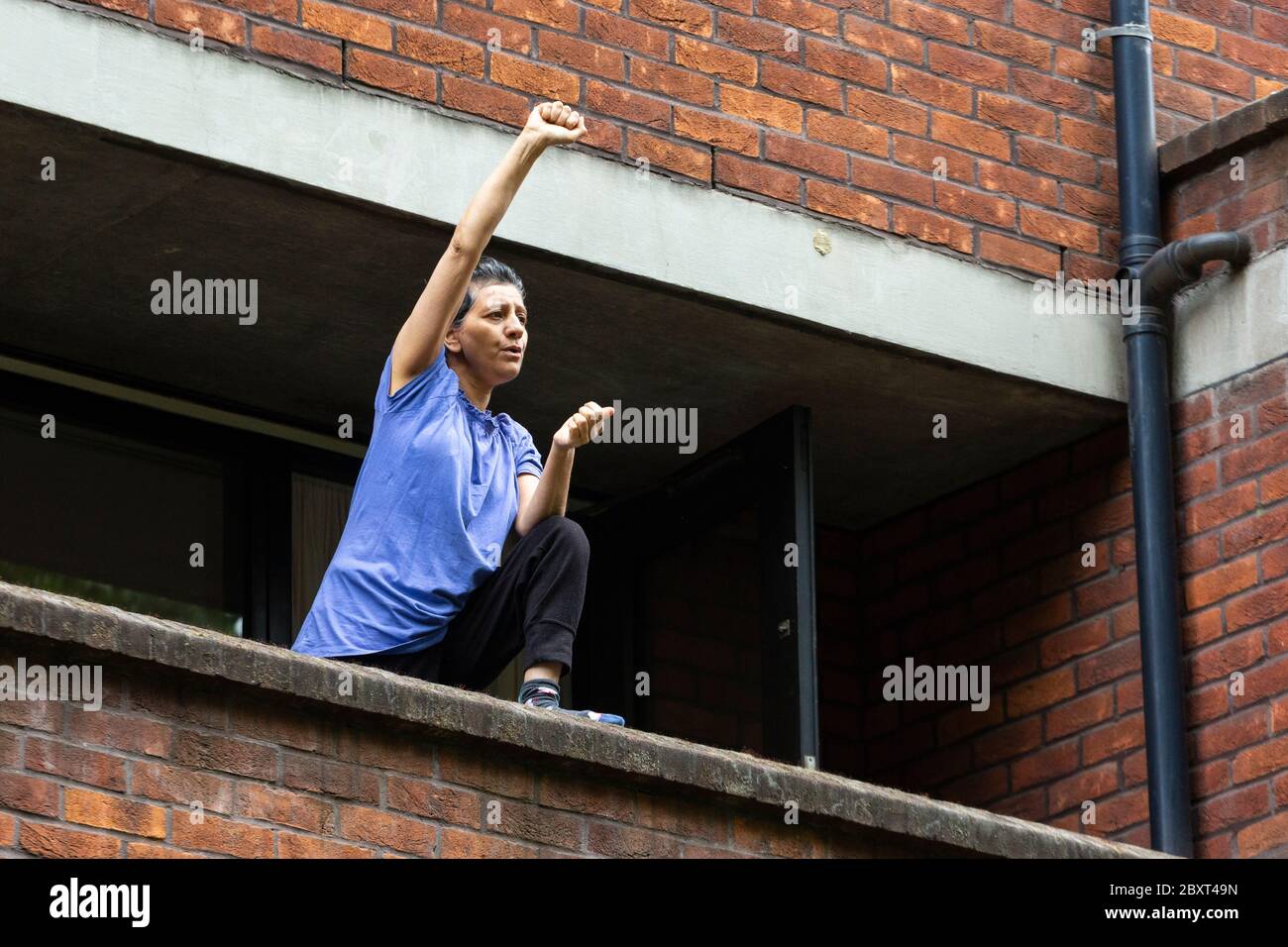 Eine Frau steht auf einem Balkon und hebt ihre Faust zur Unterstützung des Black Lives Matters Protests auf der Vauxhall Bridge Road, London, 6. Juni 2020 Stockfoto