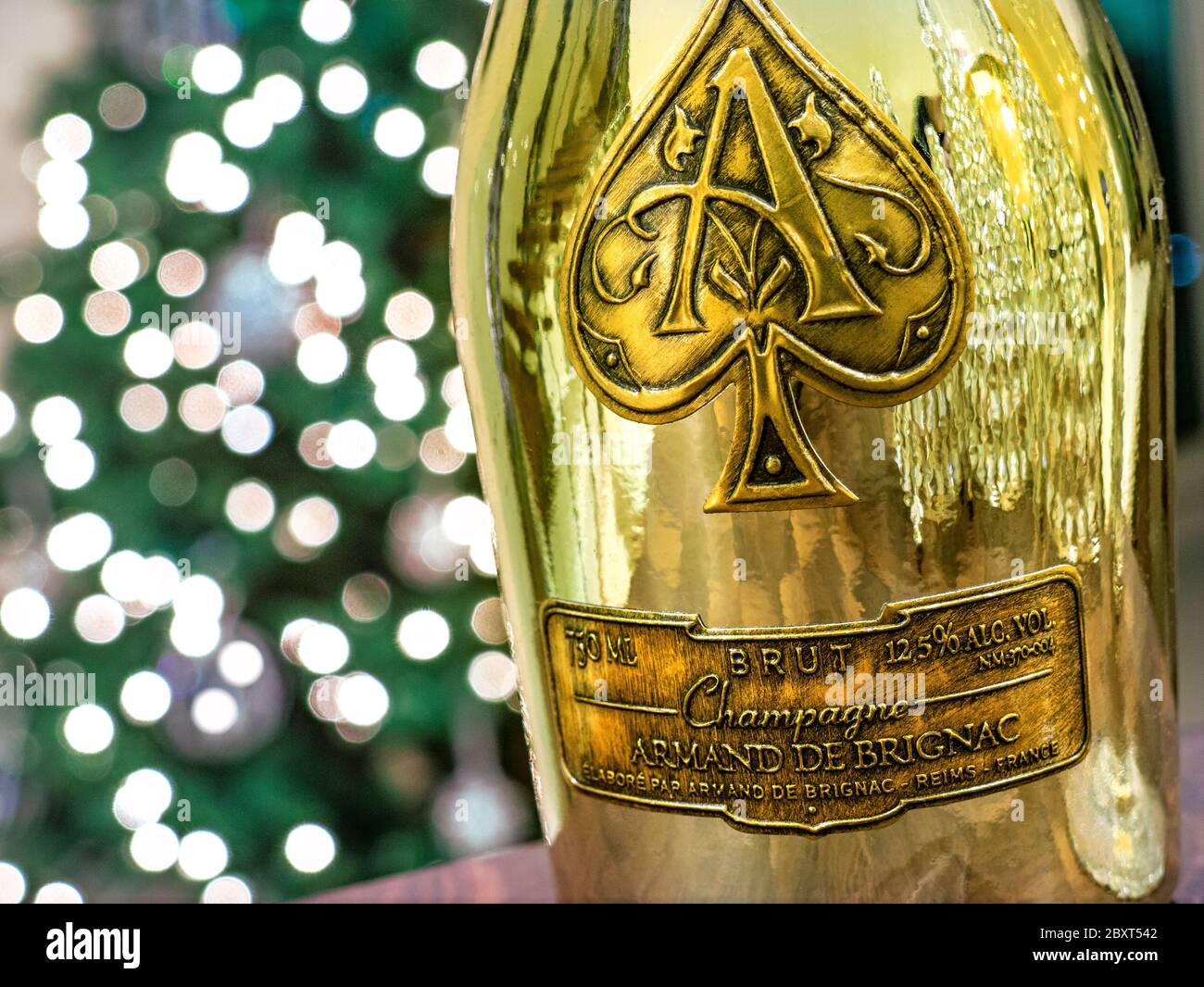 CHAMPAGNE Armand de Brignac "Ace of Spades"'' edle Luxus-Champagner-Flasche aus Metallic-Gold mit funkelnden Festlichtern dahinter Stockfoto