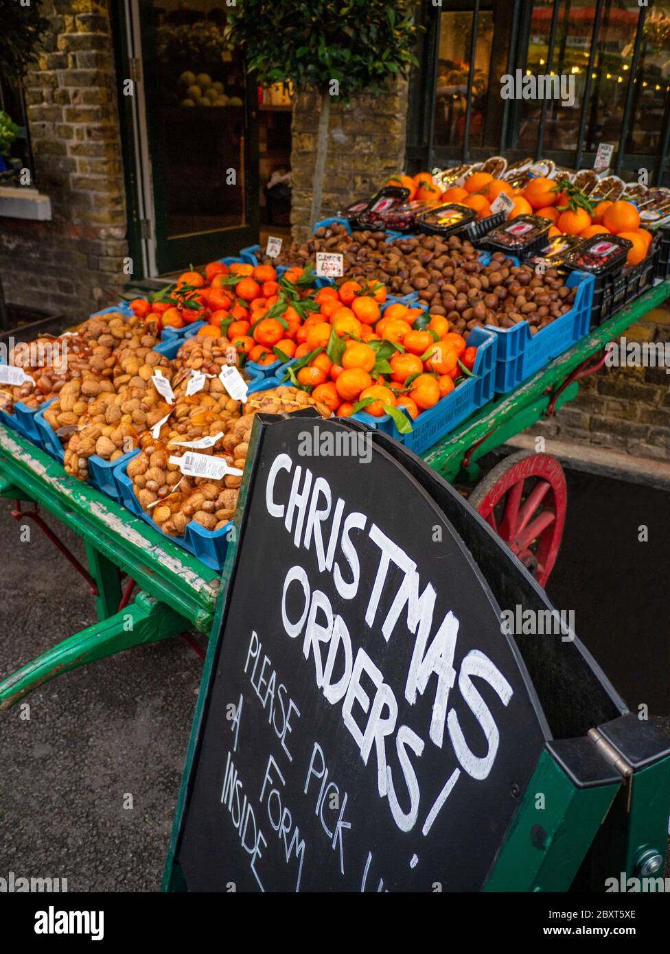 BOROUGH MARKET TRADITIONELLE HÄNDLER BARROW Auswahl an frischem Gemüse und Obst zum Verkauf, mit Tafel Werbung Weihnachtsaufträge im Borough Market Southwark London UK Stockfoto