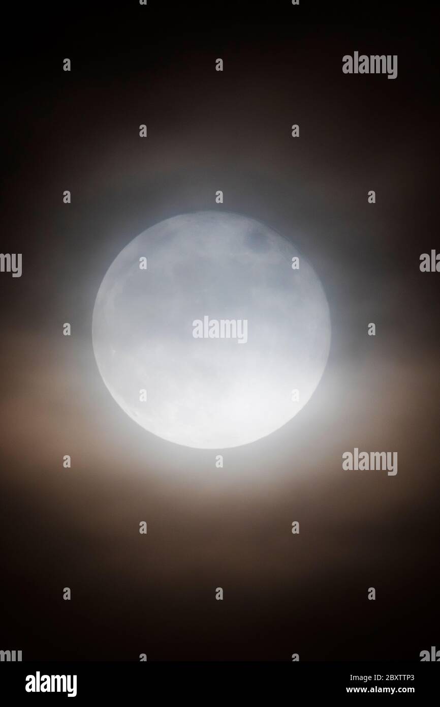 Vollmond mit Erdbeere durch Wolken über den Rocky Mountains, Salida, Colorado, USA Stockfoto