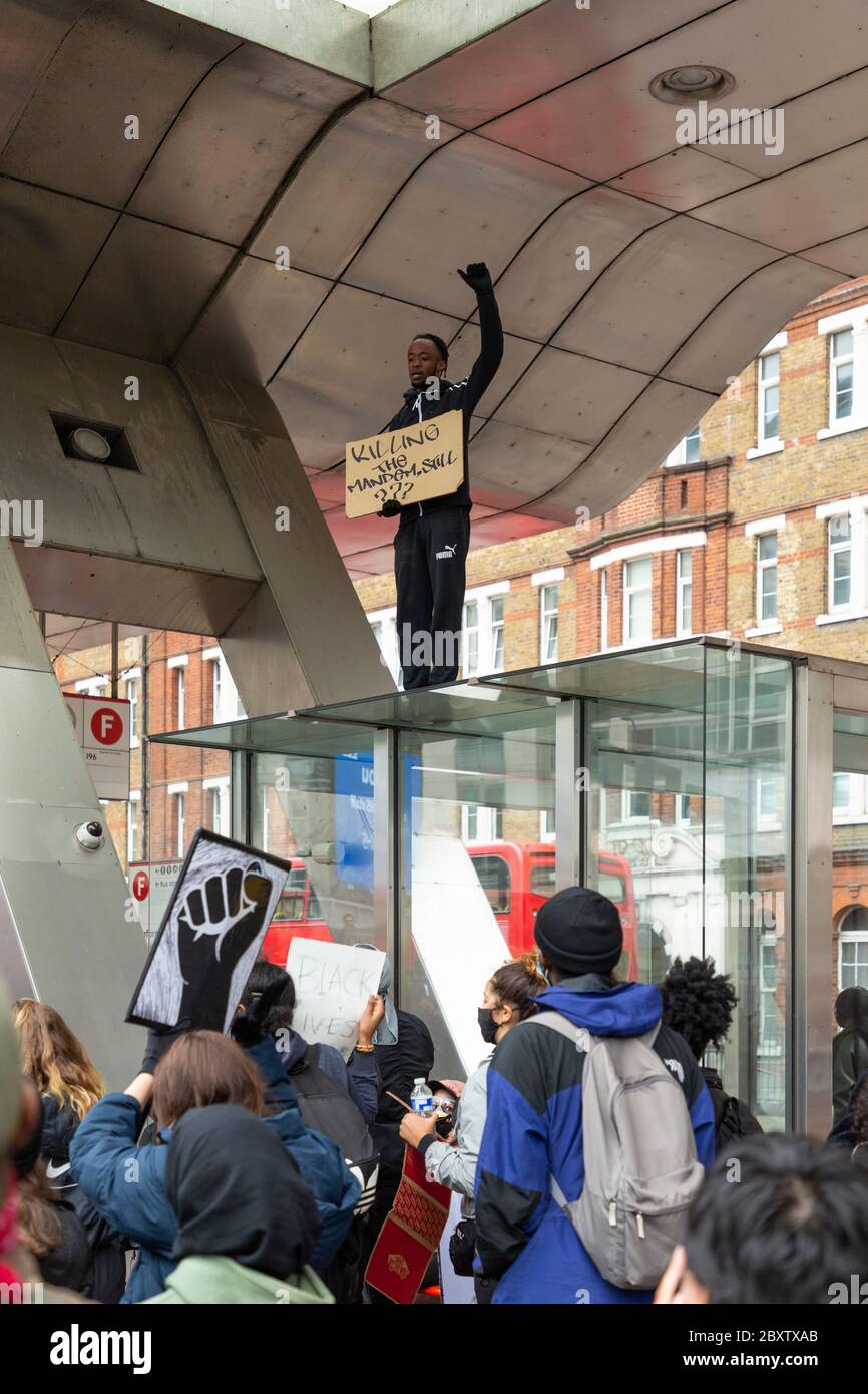 Ein schwarzer Mann steht mit erhobener Faust auf einer Bushaltestelle am Busbahnhof Vauxhall, während Black Lives Matters Protest in London, 6. Juni 2020 Stockfoto