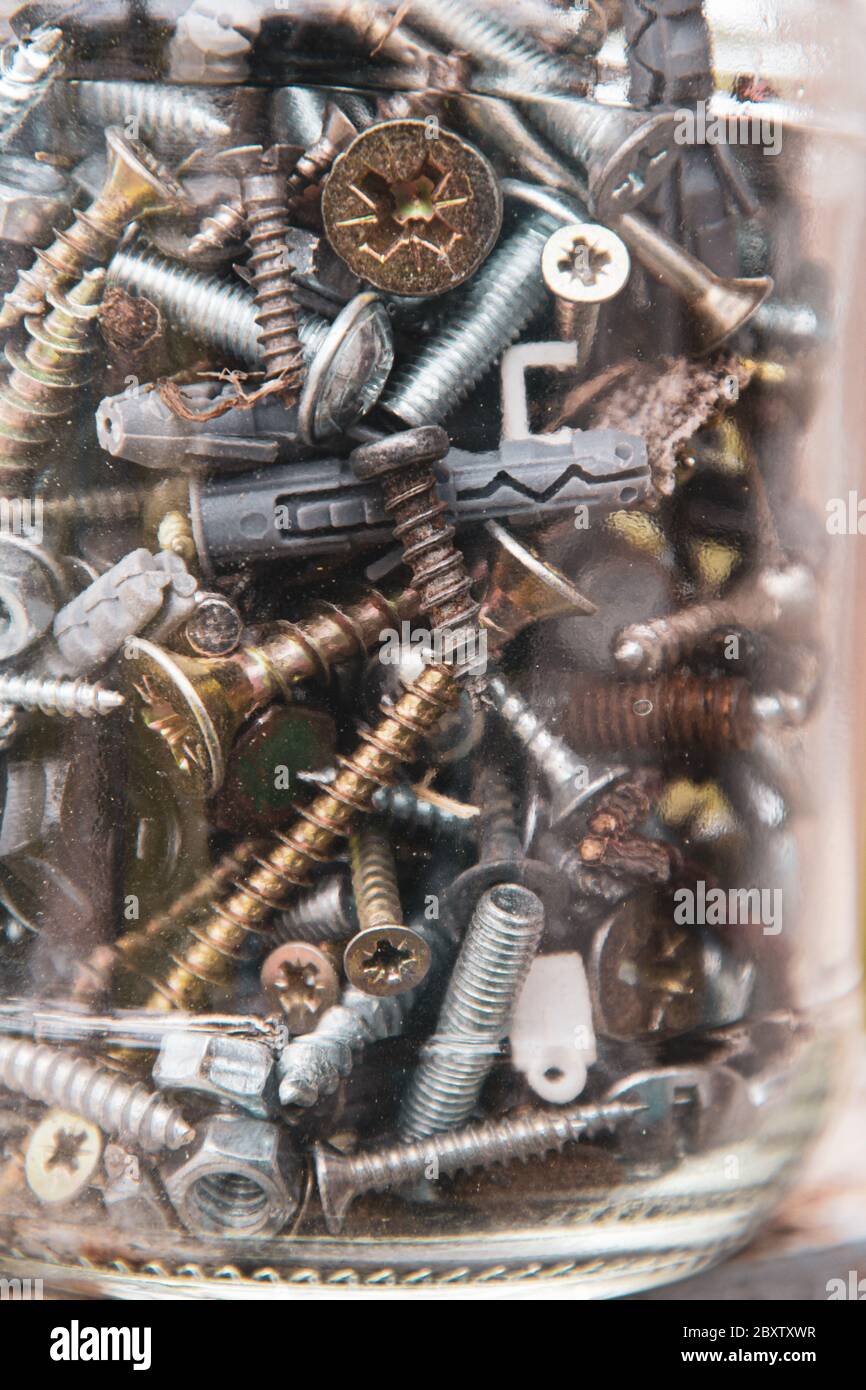 Grunge Foto durch verschwommenes dünnes Glas mit alten Metallschrauben und Muttern aufgenommen. Weichfokus auf Befestigungselemente aus Metallmaterialien mit verschwommenen Kanten des Rahmens Stockfoto