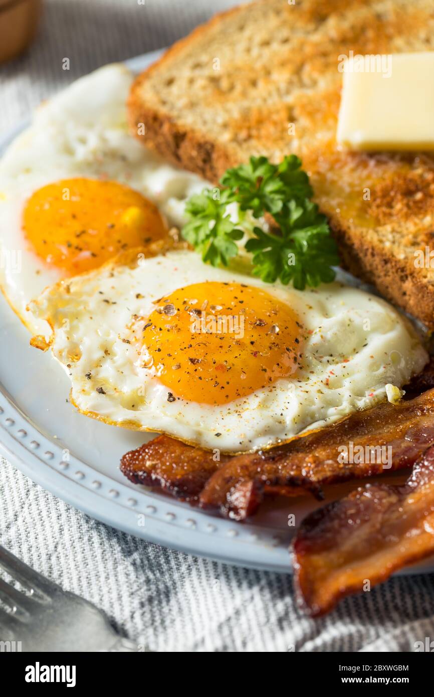 Hausgemachte Sunnyside Eier Frühstück mit Toast und Speck Stockfoto