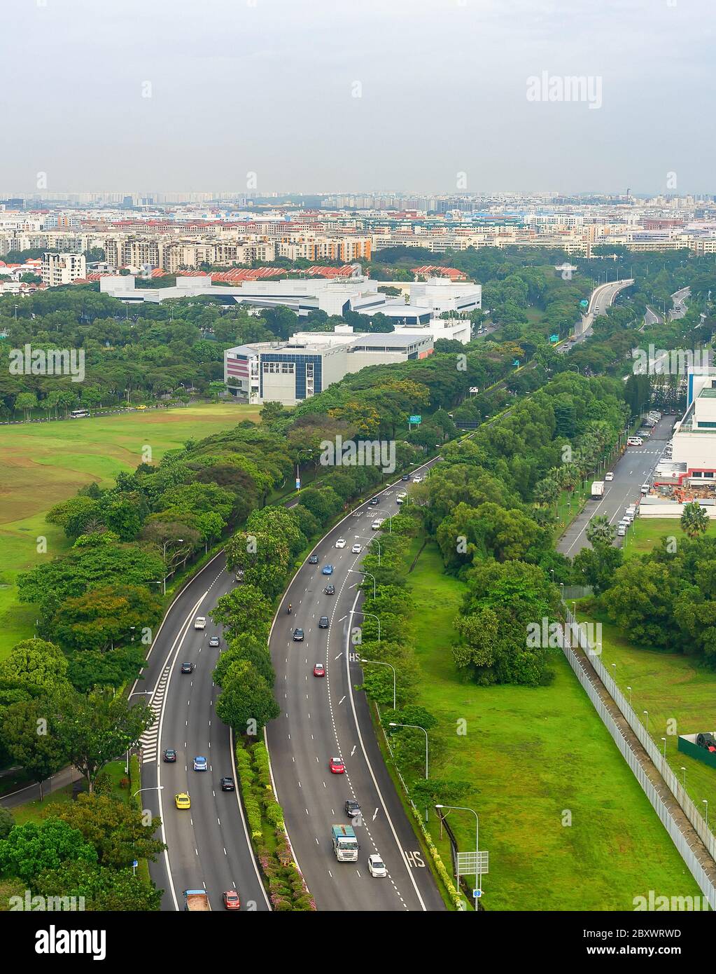 Luftaufnahme von Singapur mit PKW-Verkehr auf der Autobahn, grüne Landschaft mit modernen Stadtbild im Hintergrund Stockfoto
