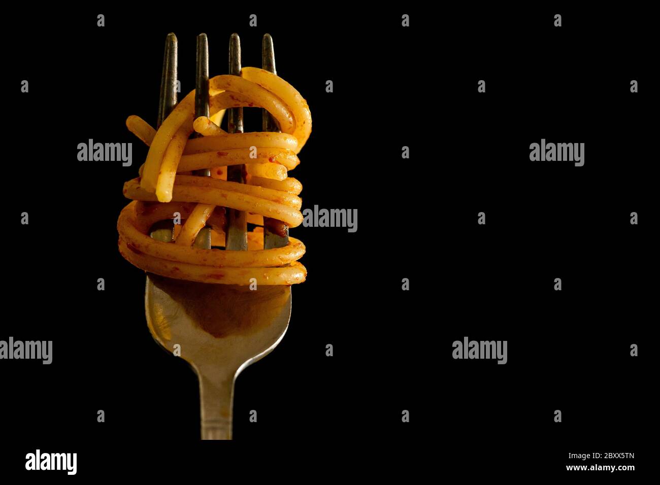 Nahaufnahme der italienischen Spaghetti auf einer Gabel mit Tomatensauce auf schwarzem Hintergrund. Typisch italienisches Essen, Stereotyp, um die italienische Kultur zu identifizieren. Hochwertige Fotos Stockfoto