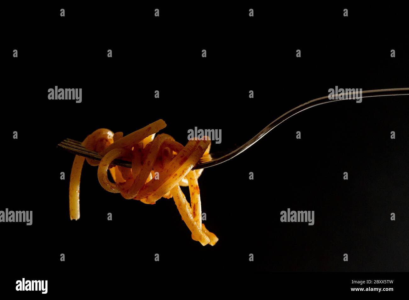 Nahaufnahme der italienischen Spaghetti auf einer Gabel mit Tomatensauce auf schwarzem Hintergrund. Typisch italienisches Essen, Stereotyp, um die italienische Kultur zu identifizieren. Hochwertige Fotos Stockfoto