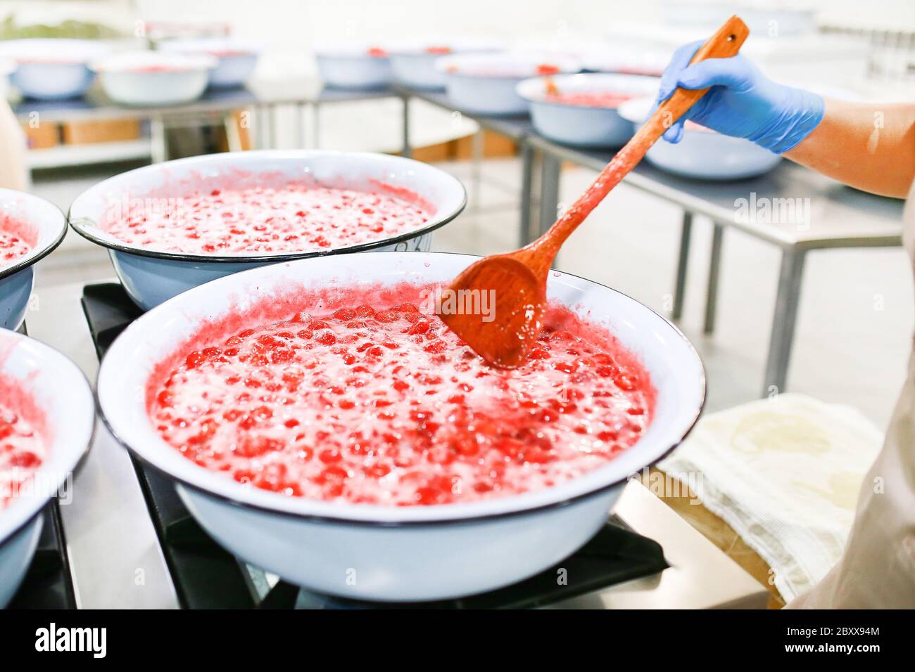 Erdbeer-Marmelade-Kochvorgang. Stau durch Holz-Löffelmischung. Herkömmliche Herstellung von organischen Staus. Stockfoto
