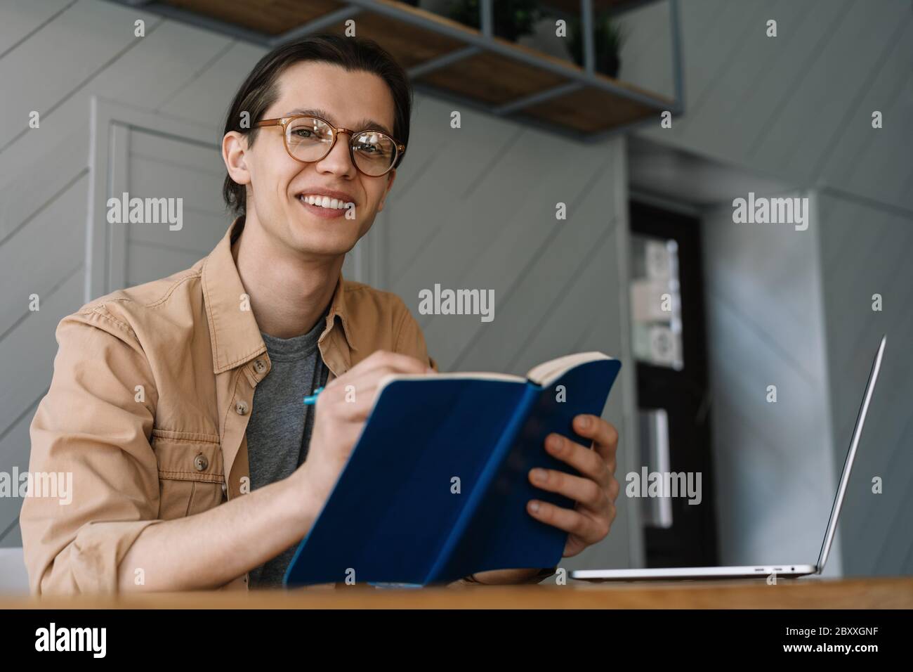 Student studieren, Fernstudium. Lächelnder Hipster Mann Notizen in Notebook, Arbeit freiberuflich Projekt von zu Hause Stockfoto