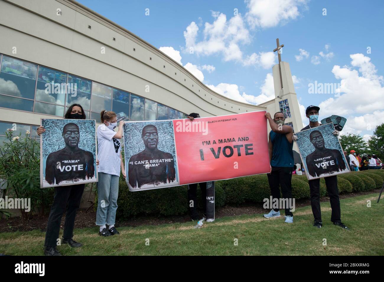 Demonstranten halten Schilder mit Bildern von George Floyd vor der Fountain of Praise Kirche, wo Tausende von Menschen warteten in der Schlange, um die öffentliche Visitation für Floyd in einem Vorort von Houston zu besuchen. Floyds Tod, verursacht durch einen weißen Polizisten, löste weltweite Proteste gegen Rassismus und Polizeibrutalität aus. Stockfoto