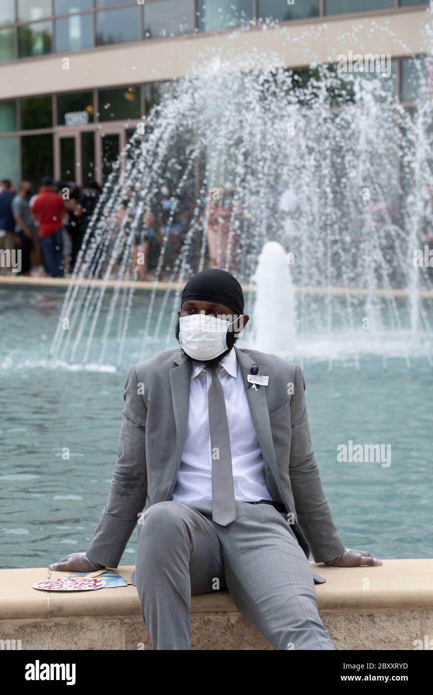 Ein junger Mann mit Gesichtsmaske macht eine Pause, bevor er die Kirche des Springbrunnens of Praise während eines öffentlichen Besuchses für George Floyd betritt. Floyds Tod vor zwei Wochen an den Händen eines weißen Polizeibeamten in Minneapolis hat Hunderte von Anti-Rassismus und Anti-Polizei Brutalität Proteste weltweit hervorgebracht. Stockfoto