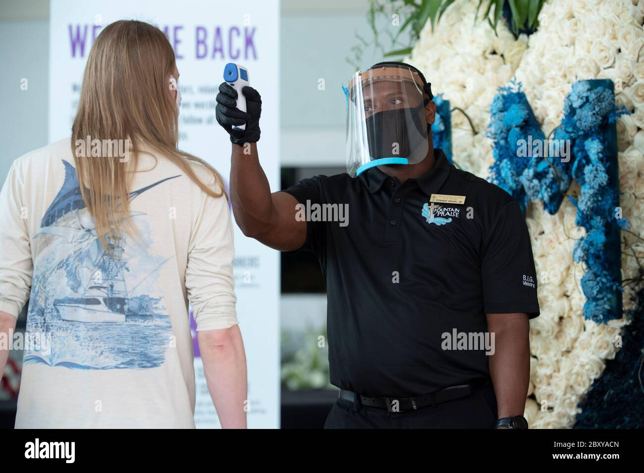 Ein Kirchenbeamter nimmt die Temperatur eines Gastes, während Tausenden eine öffentliche Betrachtung an der Brunnen des Lobes Kirche im Südwesten Houston für GEORGE FLOYD, getötet vor zwei Wochen durch einen weißen Polizeibeamten in Minneapolis, besuchen.Floyds Tod löste weltweite Proteste gegen Rassismus und Polizeibrutalität aus. Stockfoto