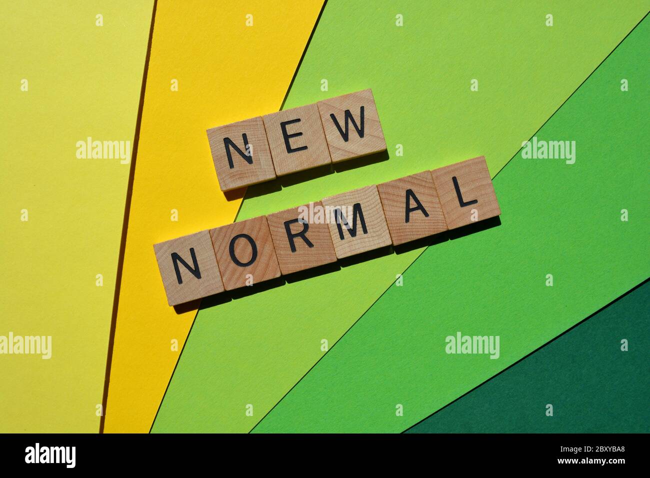 Neue normale, Wörter in 3d hölzernen Buchstaben auf gelbem und grünem Hintergrund isoliert Stockfoto