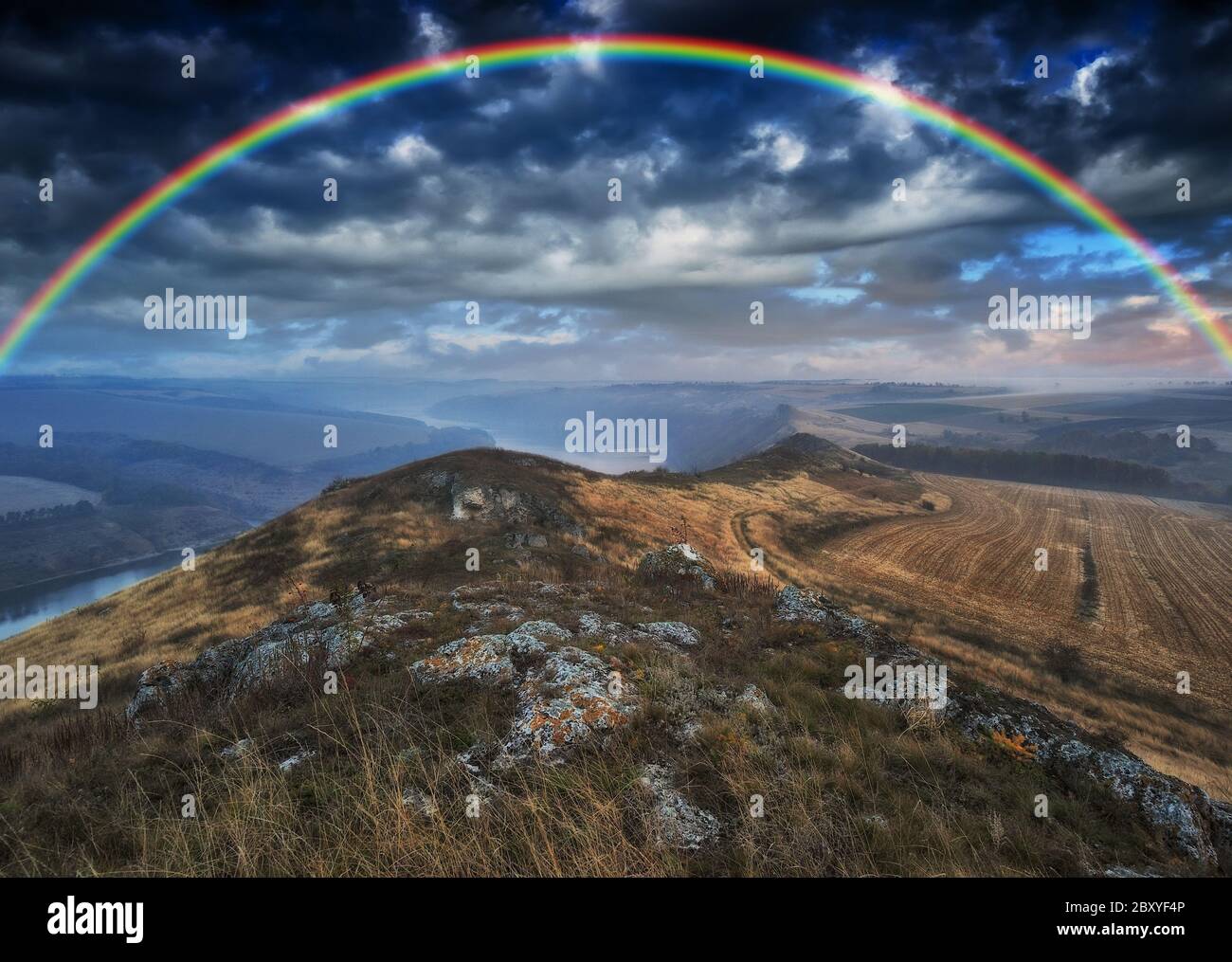 Regenbogen mit Wolken über einem Felsen Stockfoto