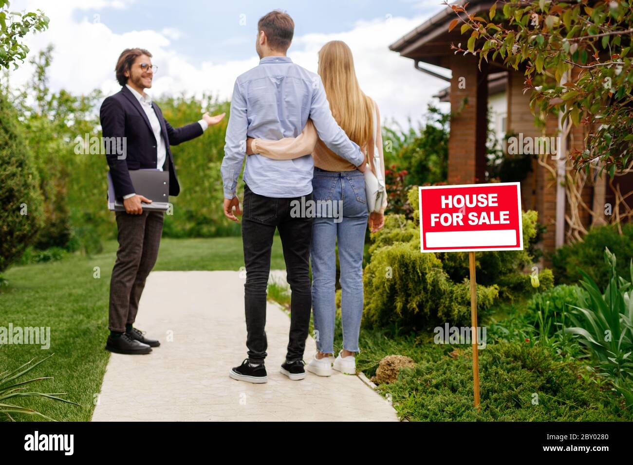 Immobilien-Broker zeigt Haus zum Verkauf an junge Paar, außerhalb Stockfoto