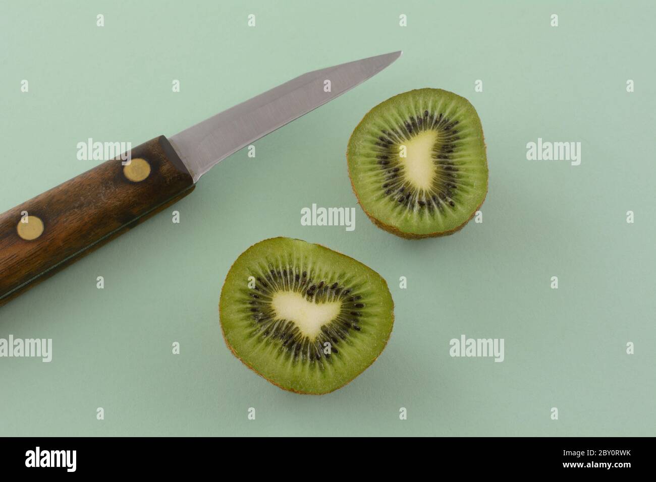 Kiwi Fruchthälften und Küchenmesser auf hellgrünem Hintergrund Stockfoto