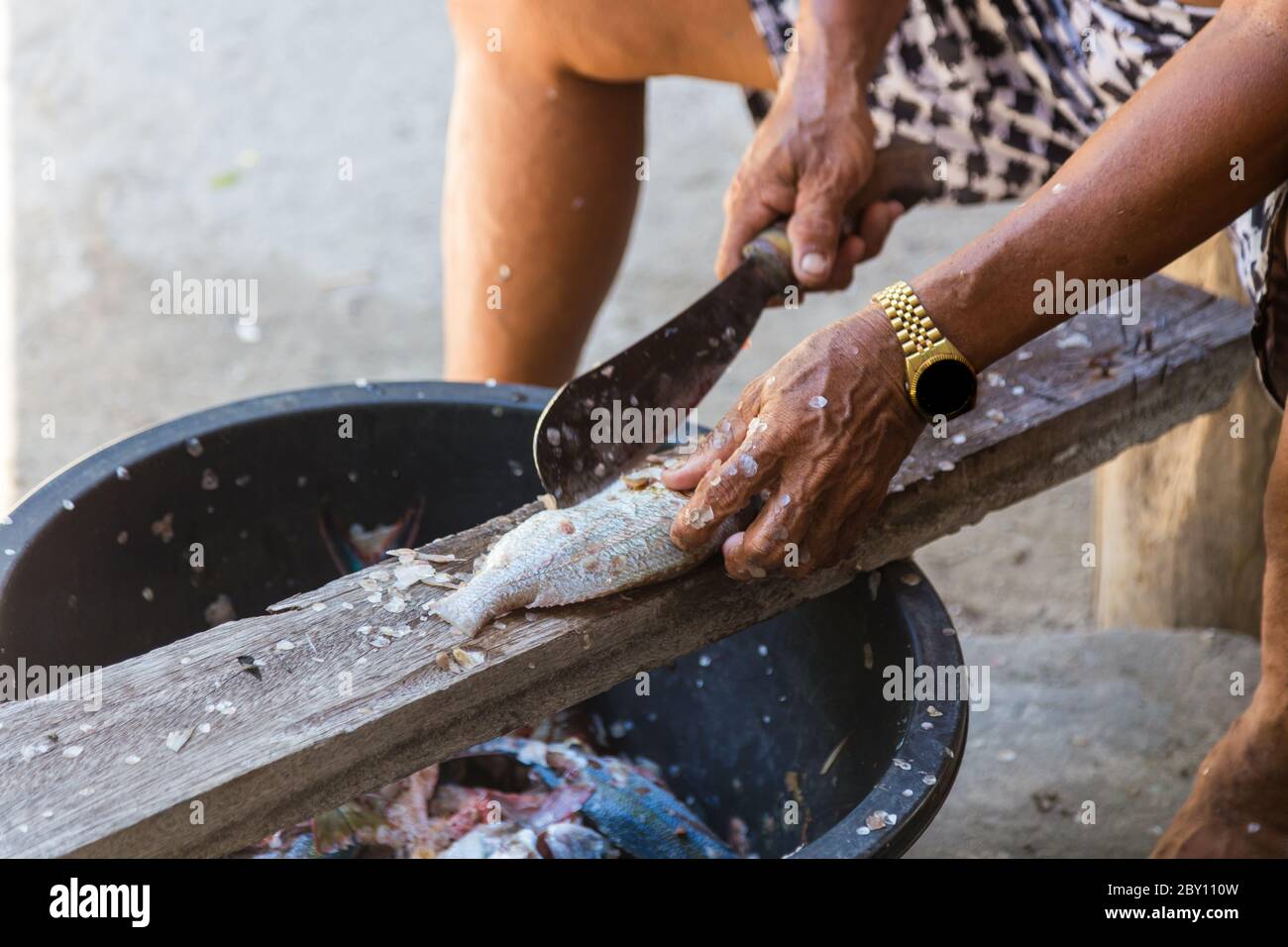 Lokale alte Mann Hand schneiden Fisch auf ihre eigene Weise in Mantanani Island, Kota Belud, Sabah, Borneo Stockfoto