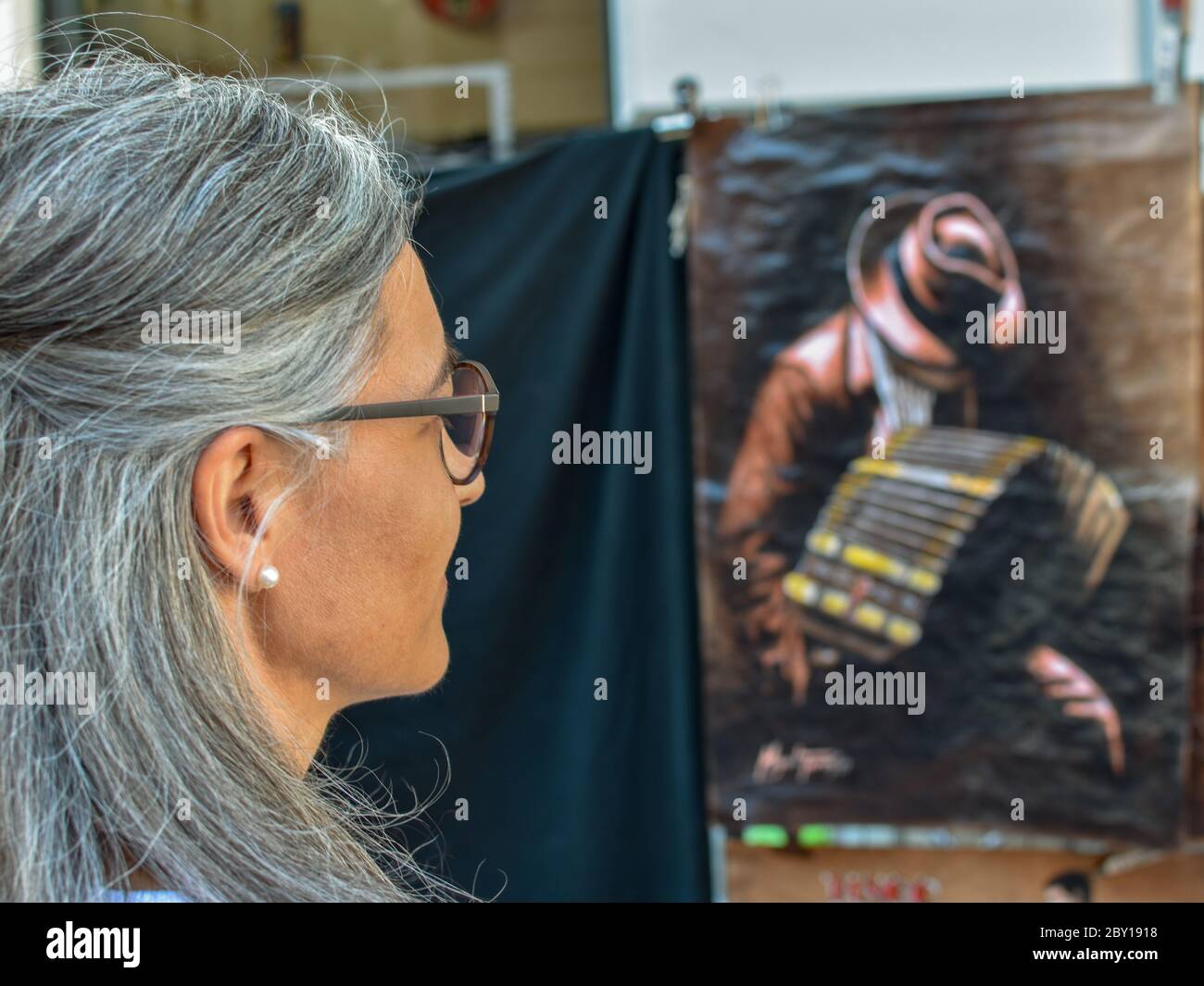 Eine Touristen-Dame mittleren Alters, die sich Kunstwerke anschaut, die einen Tango-Spieler auf dem Kunsthandwerksmarkt San Telmo in Buenos Aires zeigen Stockfoto