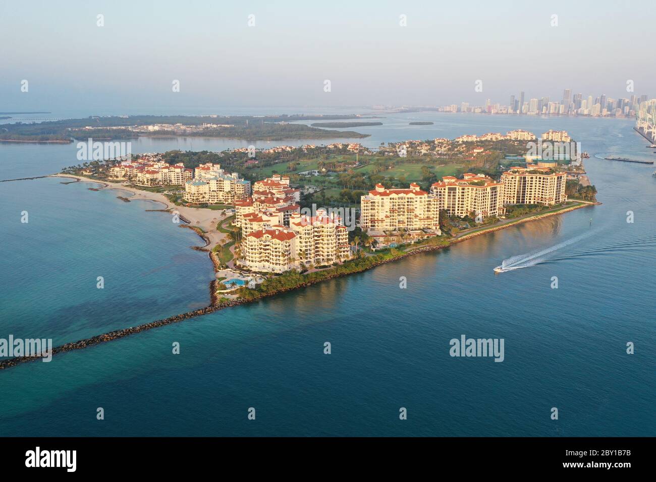 Luftaufnahme von Fisher Island und Government Cut mit der Skyline von Miami und Port Miami im Hintergrund bei Sonnenaufgang. Stockfoto