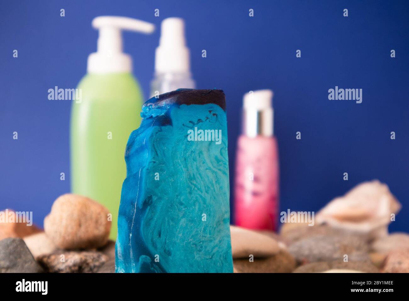 Dünnes flaches Stück blauer Minze handgemachte Seife, die auf Kiesel und Toilette liegt Stockfoto