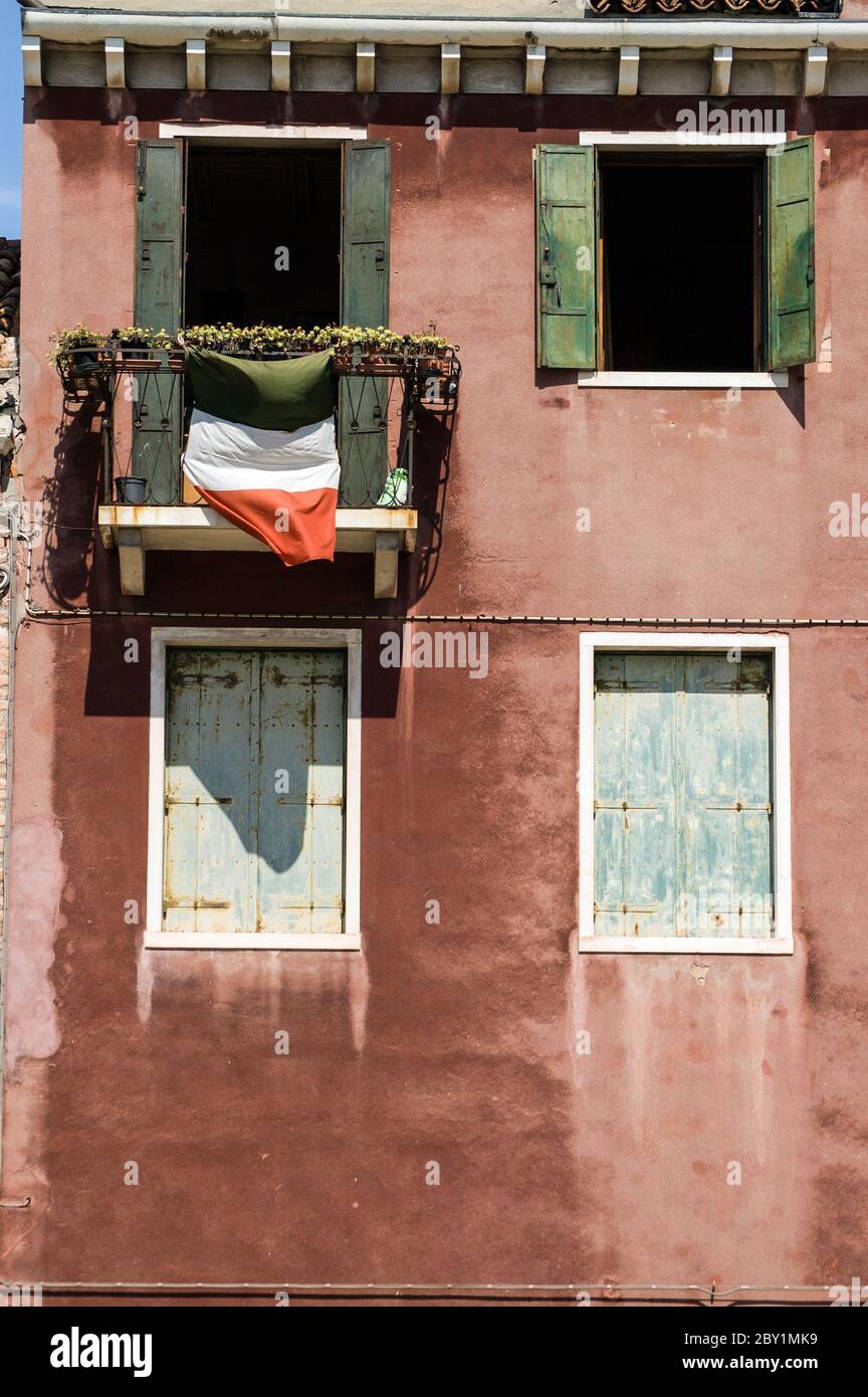 Die italienische Nationalflagge flattert von einem Balkon eines Hauses in Venedig. Stockfoto