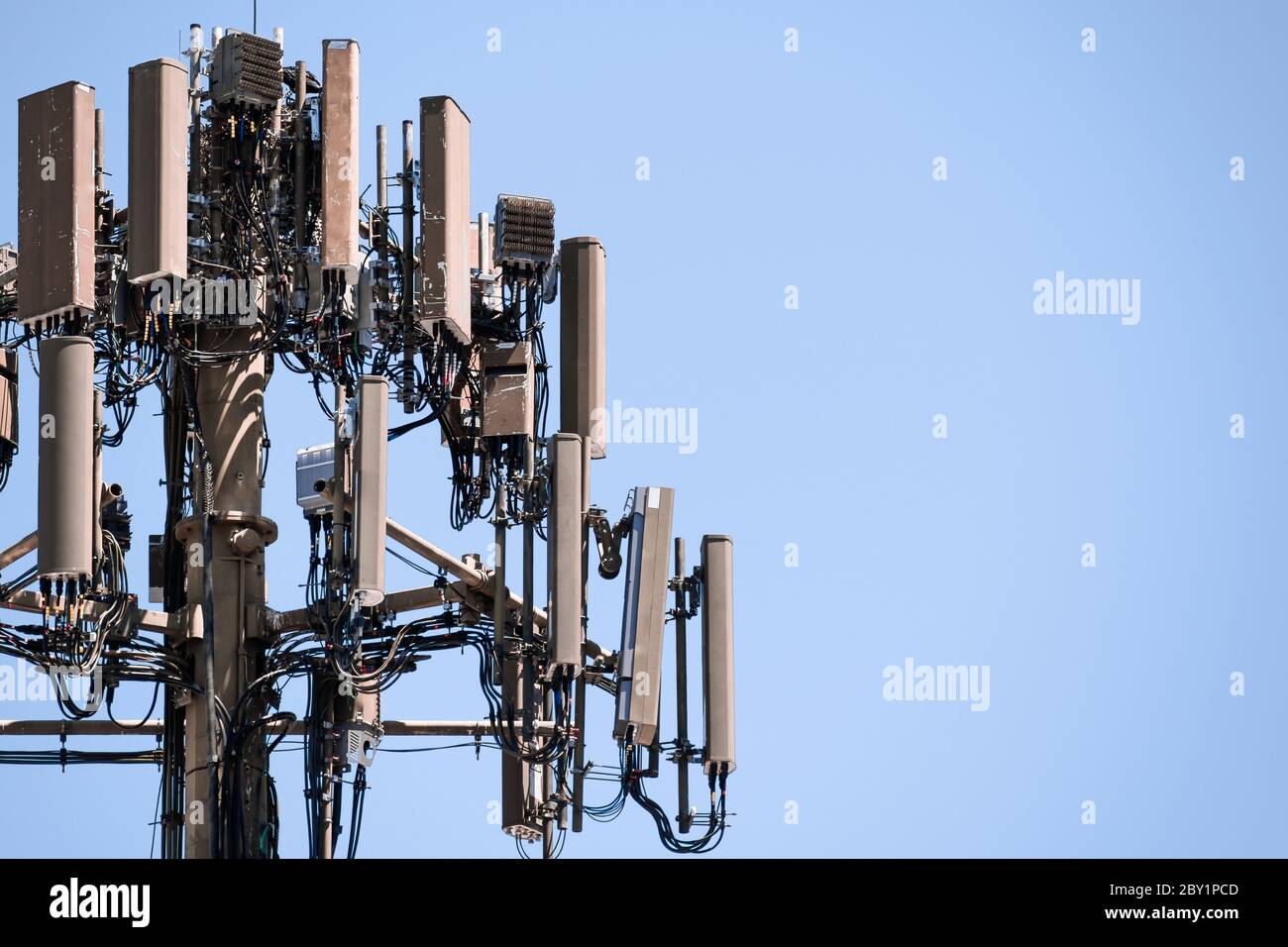 Nahaufnahme des Mobilfunkmastes mit Antennen für drahtlose Kommunikation; blauer Himmel und Kopierfläche rechts Stockfoto