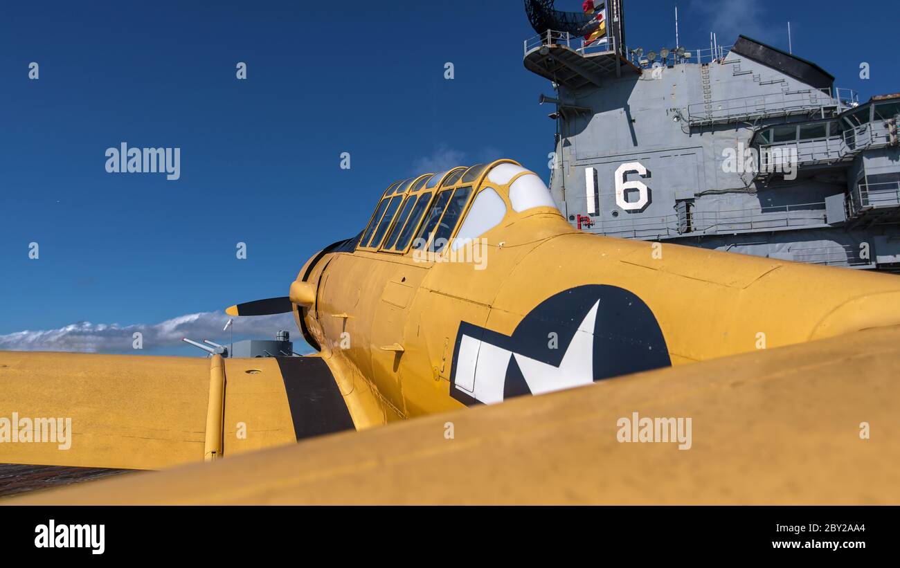 Gelbes T 6 Texan Trainingsgerät auf dem Lexington Flugzeugträger-Flugdeck in Texas mit Kontrollturm im Hintergrund. Stockfoto