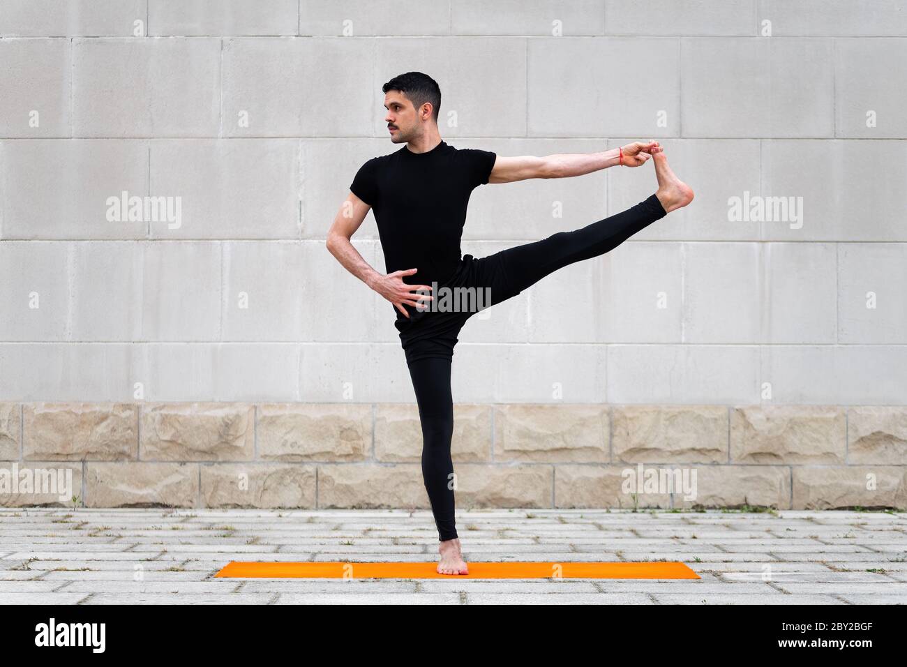 Ausgestreckte Hand zur Big Toe Pose. Attraktiver latein, der in einer Stadt Yoga im Freien macht. Stockfoto