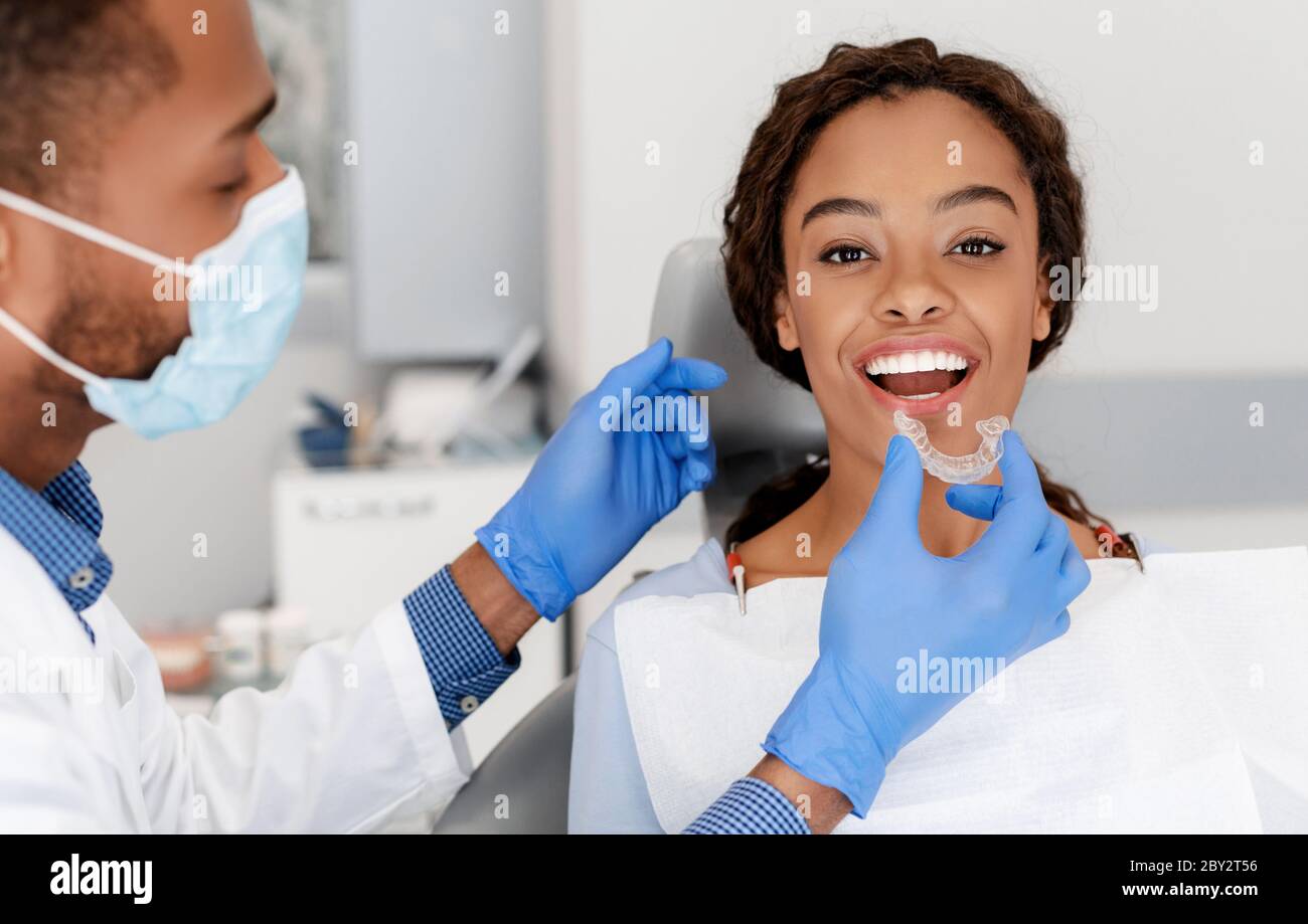 Zahnarzt, der unsichtbare Ausrichter auf die Zähne eines weiblichen Patienten anwendet Stockfoto