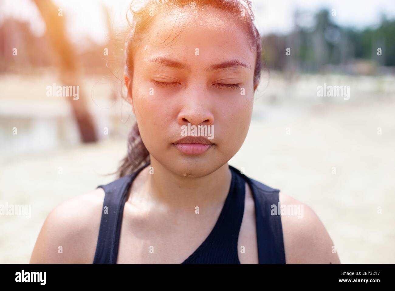 Portrait der asiatischen jungen attraktiven Yogi Frau mit geschlossenen Augen in meditierender Pose, Entspannungsübung, Training, Tragen von Sportbekleidung, schwarzes Top Stockfoto