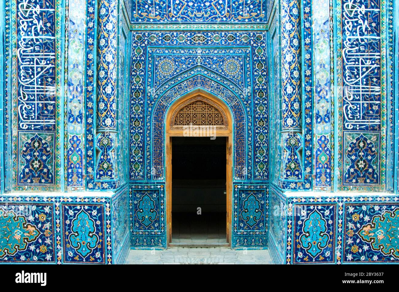 Dekorative muslimische Mosaikfliesen am gewölbten Eingang mit offener Tür von Schah-i-Zinda in Samarkand, Usbekistan Stockfoto